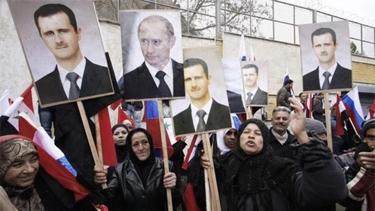 hững người biểu tình ủng hộ chính quyền Syria giơ cao hình ảnh của ông Bashar al-Assad và Vladimir Putin bên ngoài đại sứ quán Nga tại Damascus.