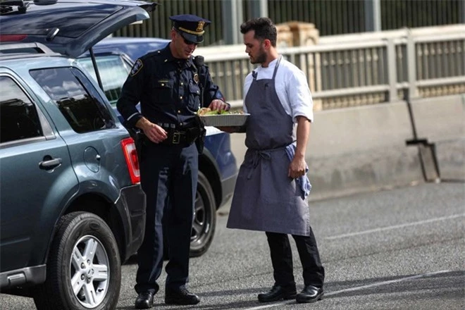 Một nhân viên phục vụ tại nhà hàng Canlis, gần khu vực xảy ra tai nạn, đem đồ ăn tới cho các cảnh sát làm việc tại hiện trường. 