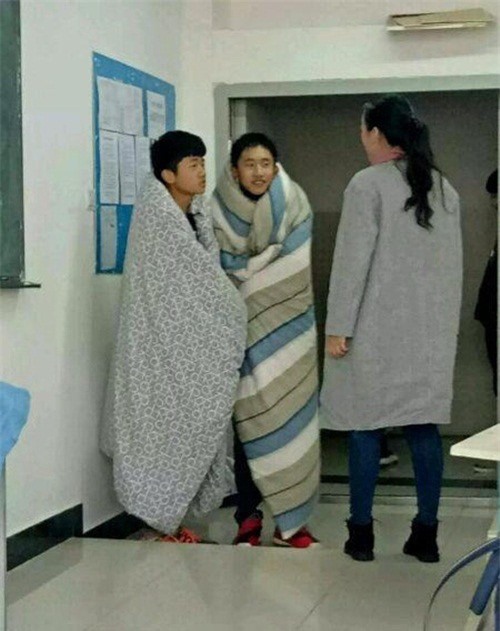 Thời tiết trở lạnh, hai nam sinh quấn chăn đến trường