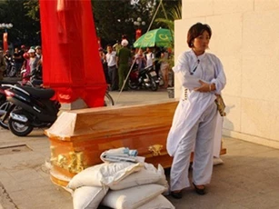 Một phụ nữ mang quan tài đặt trước cửa ngân hàng gây náo loạn